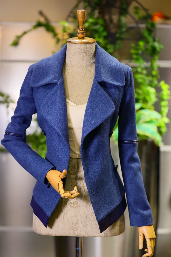 Services-03 Stylish blue women's jacket displayed on a mannequin in a fashion shop, showcasing modern textile design.