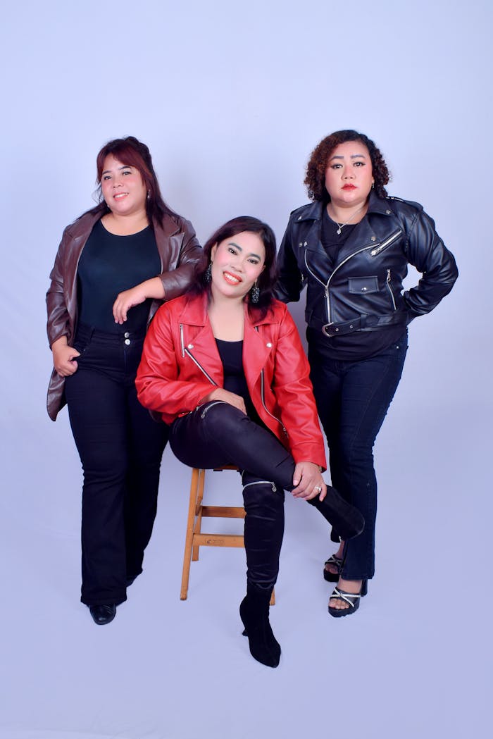 digital Three confident women posing together in leather jackets against a studio backdrop.